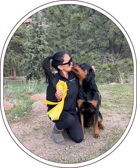 A woman kneeling down next to a dog.