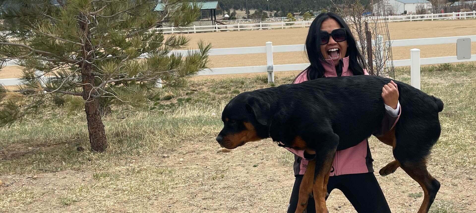 A woman holding onto a large black dog.