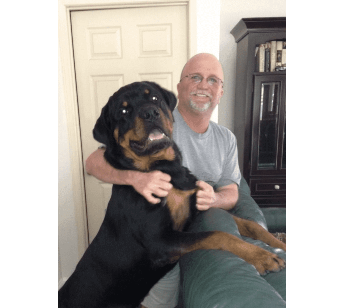 A man sitting on the couch with his dog.