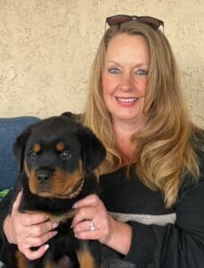 Woman holding an adorable Rottweiler puppy.