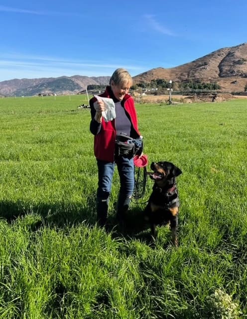 Woman with Rottweiler in grassy field.